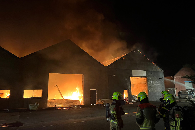 Twee loodsen in brand met brandweermannen aan het werk