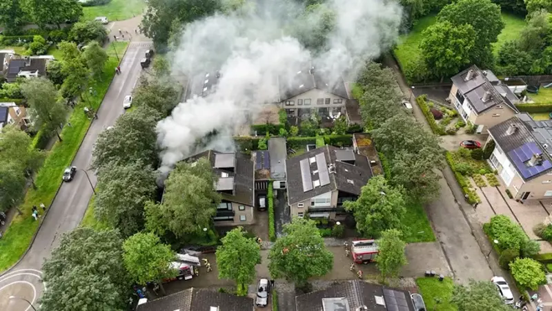 Woning van bovenaf met rookwolk over de wijk