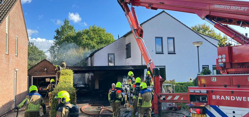 brandweerlieden blussen met hoogwerker de garage van de woning