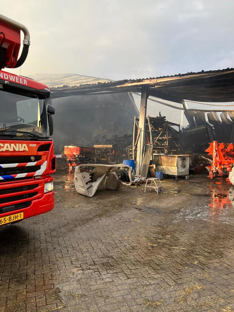 In de schuur is de brandweer bezig met het loshalen van het hooi dat brandt