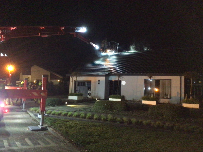 Brandweer blust vanaf hoogwerker de woning.