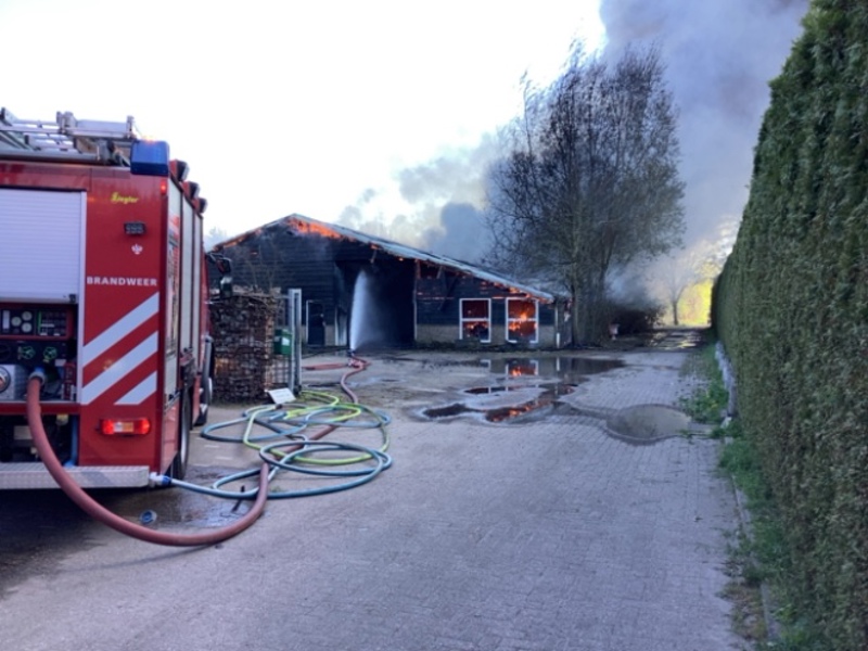Brandende schuur en brandweerauto ernaast